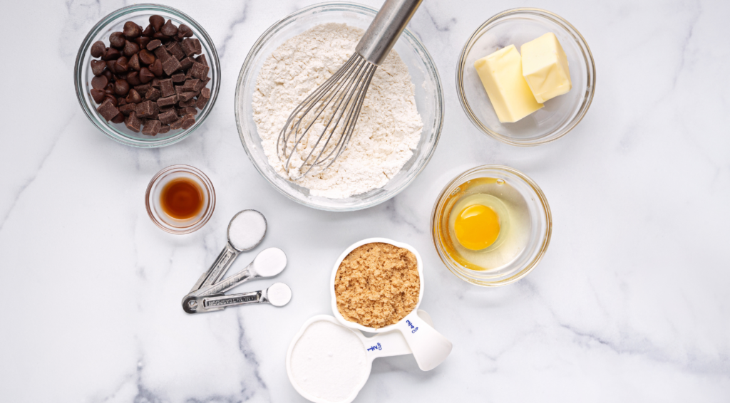 several bowls holding the ingredients for chocolate chip cookies